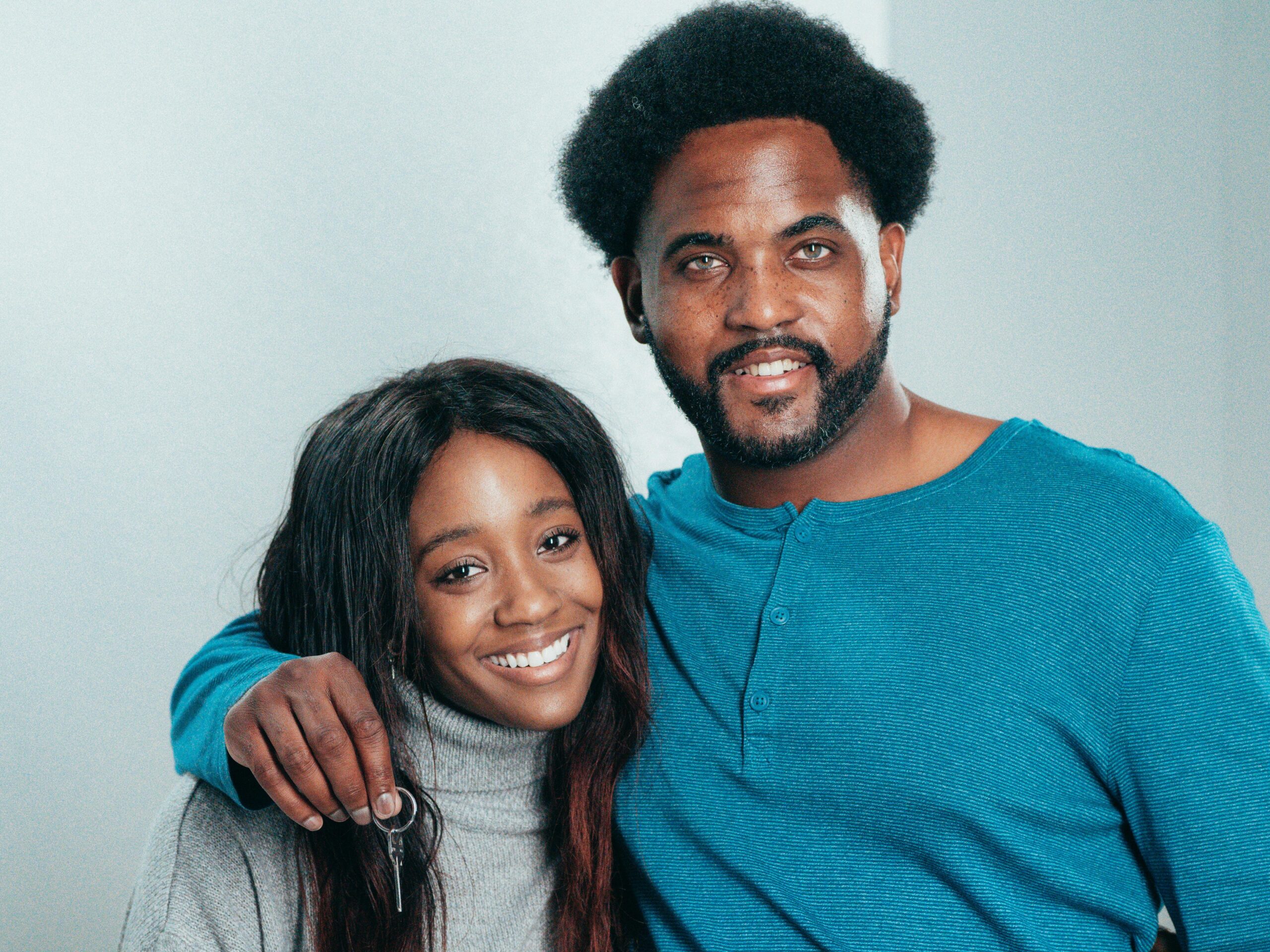 Smiling African American couple holding keys, celebrating home ownership.